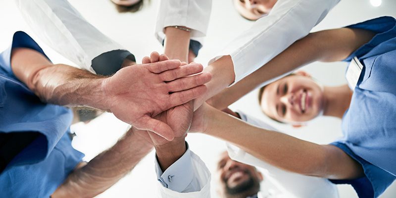 Shot of a diverse team of doctors joining their hands together in unity