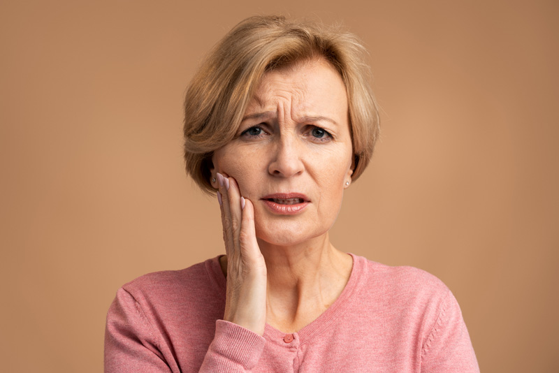 portrait of unhealthy woman pressing sore cheek suffering acute toothache periodontal disease cavities or jaw pain indoor studio shot dental problems concept