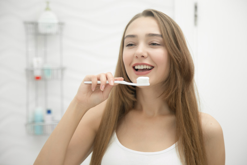 portrait of young smiling girl cleaning her teeth