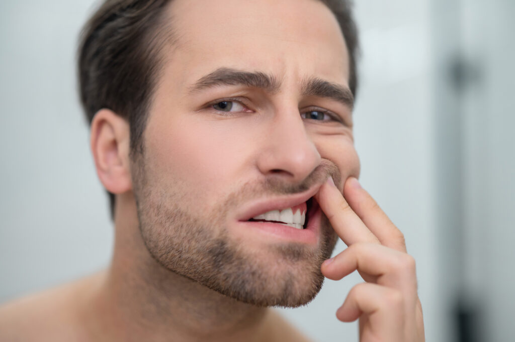 problemas dentales hombre revisando sus dientes mirando perturbado