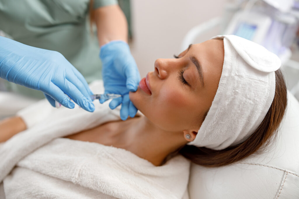 Young woman receiving hyaluronic acid injection in beauty salon